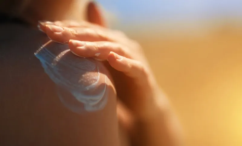 woman applying sunblock cream on her shoulder