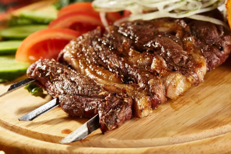 breast of lamb skewers garnished with vegetable and potato