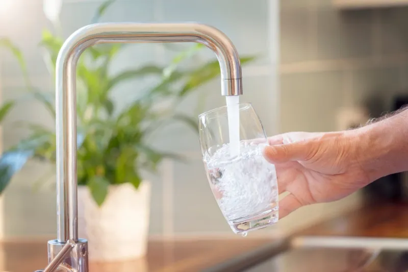 filling up a glass with clean drinking water from kitchen faucet