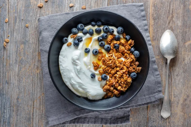 appetizing homemade muesli with berries and yogurt served in bowl on wooden background