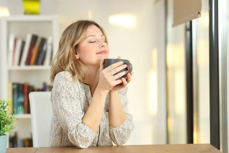 portrait of a woman breathing and holding a coffee mug at home