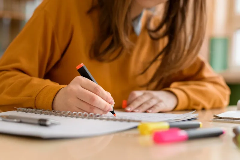 young unrecognisable female college student in class, taking notes and using highlighter focused student in classroom authentic education concept