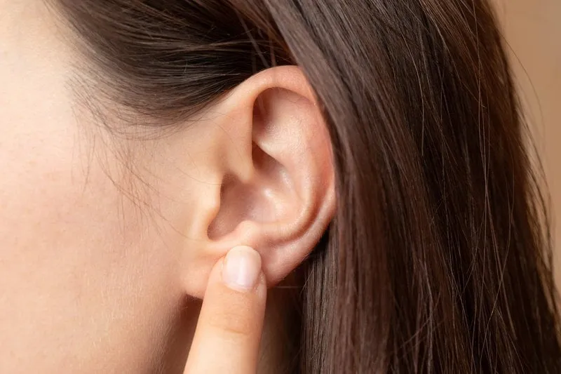 woman's finger touching her ear