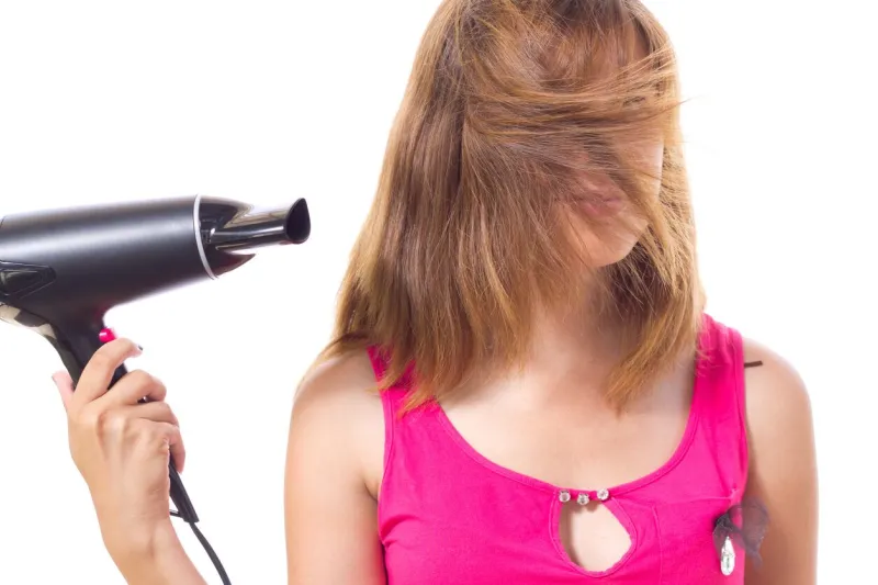 girl dries hair with electrical appliance