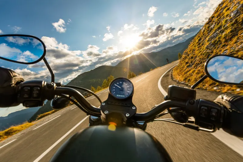 motorcycle driver riding in alpine highway, handlebars view, austria, central europe
