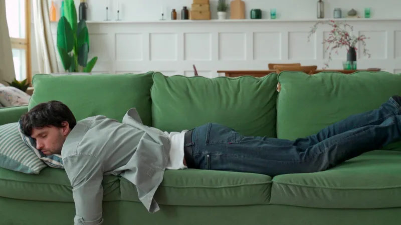 exhausted young man came home after work flopped down on sofa