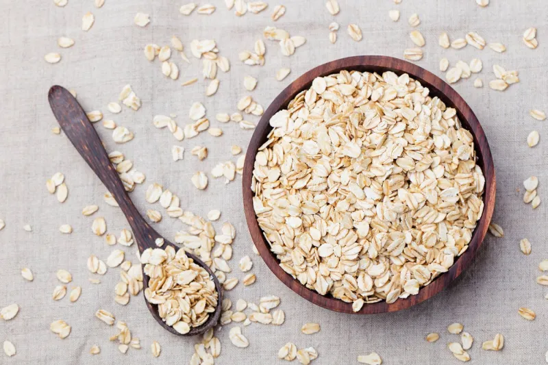 healthy breakfast organic oat flakes in a wooden bowl grey textile background top view copy space