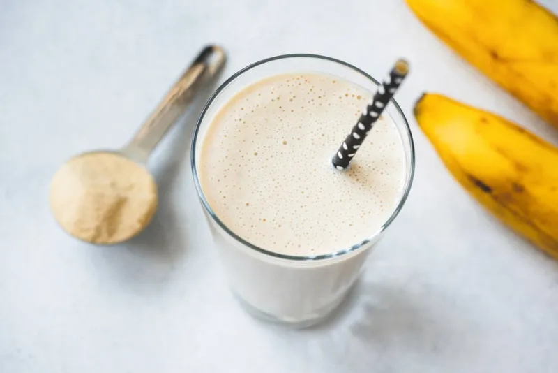 vegan protein banana shake or smoothie in glass top view, selective focus