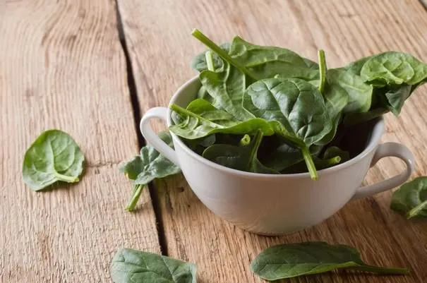 épinards dans le bol sur le fond de bois