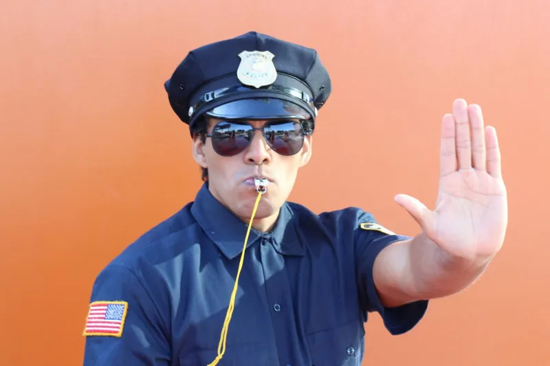 stern police officer blowing a whistle