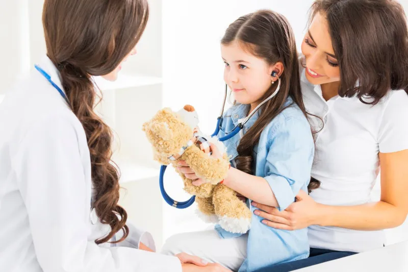 mother and daughter at pediatrician office, girl examinate heart beat of teddy bear with stethoscope