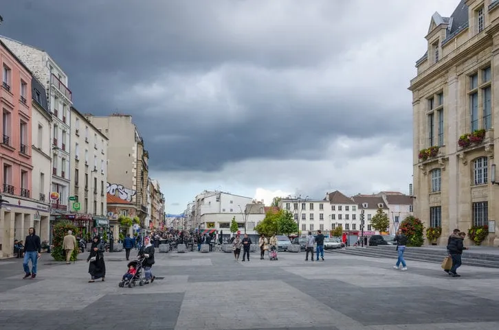 saint-denis, france - september 14, 2015  people are walking in front of the city hall which overlooks place victor hugo with rue de la republique in the distance saint-denis is a suburb of the french capital, paris