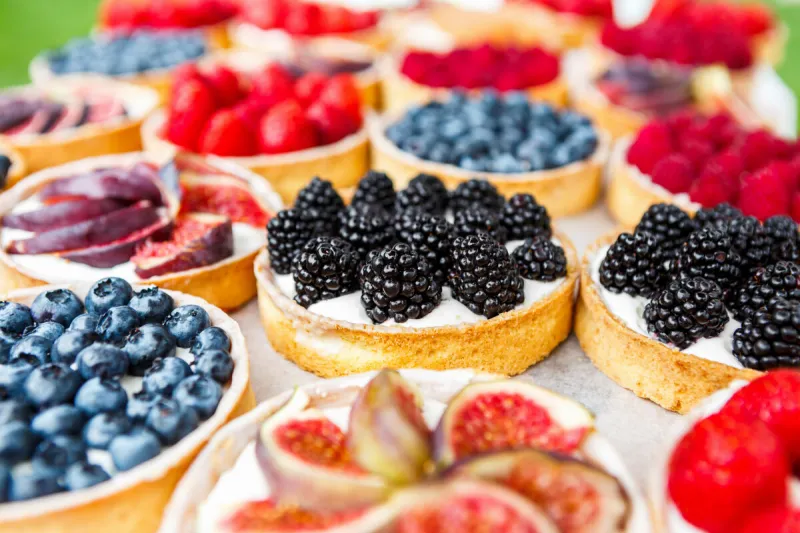 fruit and berry tarts dessert tray assorted closeup of beautiful delicious pastry sweets with fresh natural blackberries and figs french bakery catering filtered, shallow depth of field