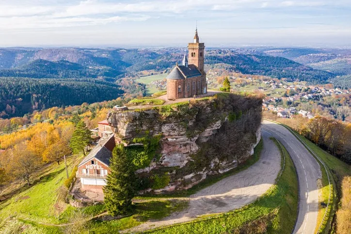 beautiful autumn aerial view of st leon chapel dedicated to pope leo ix atop of rocher de dabo or rock of dabo, red sandstone rock butte, and moselle-vosges mountains and valleys lorraine, france