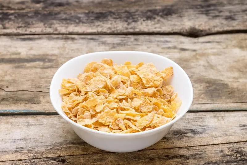 flocons de maïs dans un bol blanc sur fond de bois énergie saine ood