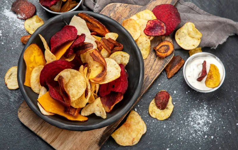 bowl of healthy colorful vegetable chips on dark background, top view