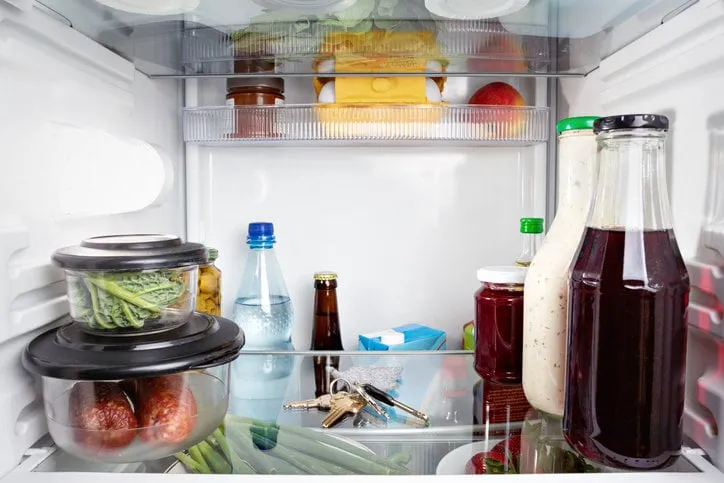 photo of the inside of a refrigerator with a closed door with a bunch of keys between groceries