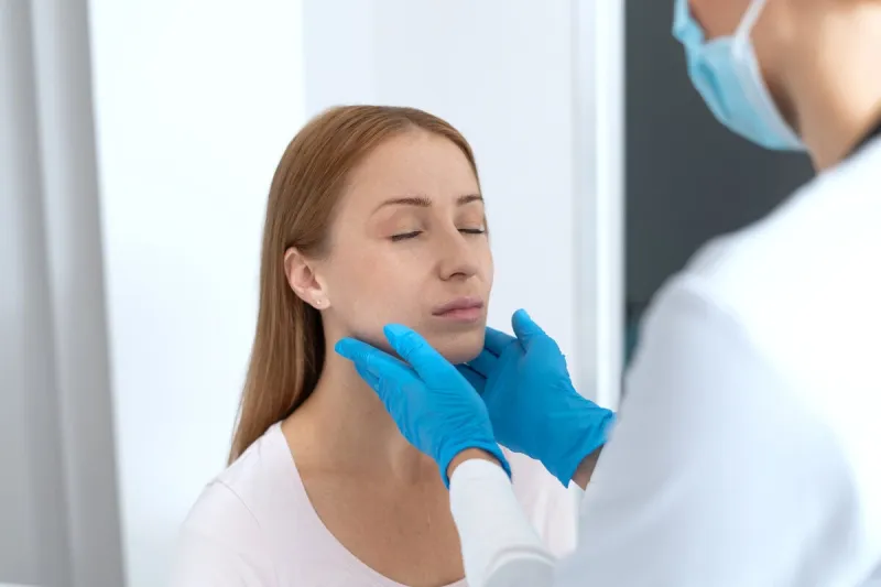 general practitioner in protective gloves touch the neck of sick female woman visit family doctor in private clinic health problems, patient examination and treatment prescription concept