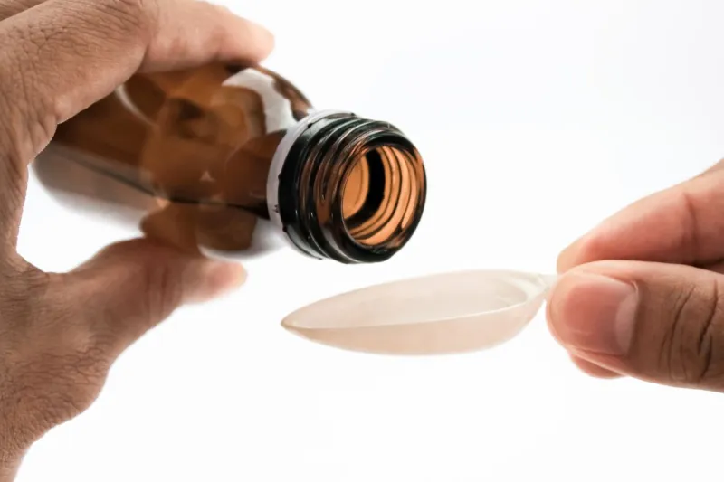 syrup medicine is easy to use syrup medicine for babies syrup medicine with a measuring cup syrup medicine pouring with isolated white background