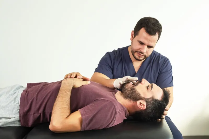 physiotherapist performing a jaw examination on a patient