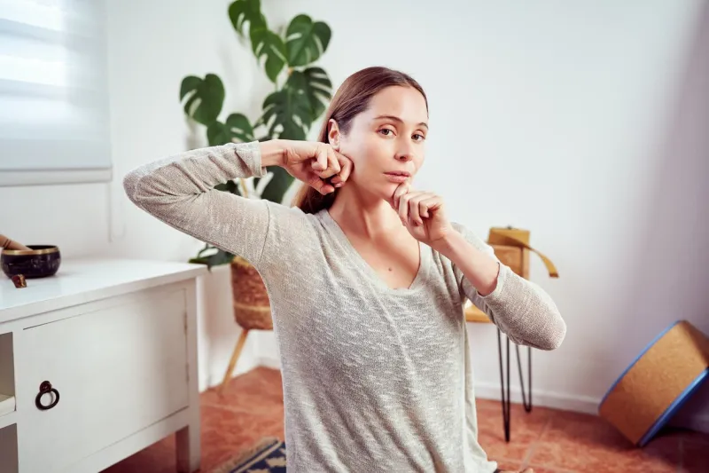 caucasian woman massaging her jaw and face portrait, facial yoga and anti aging concept