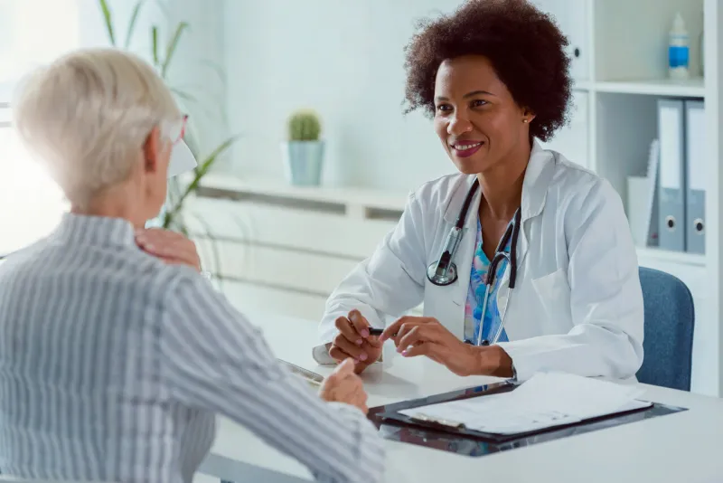 a female doctor sits at her office and examining elderly female