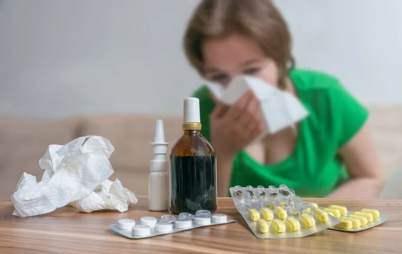 pills in front of ill woman who has flu or cold