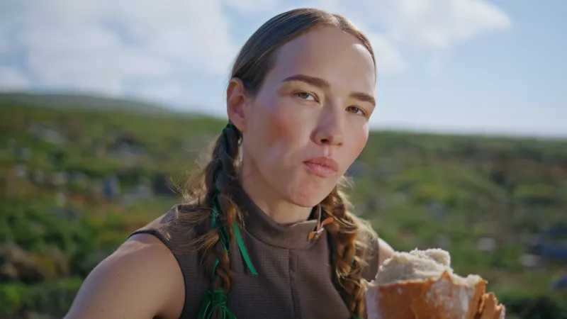 woman tasting delicious bread on green hill closeup countryside girl smelling loaf chewing crispy bakery in sunlight outdoors hungry serene traveler enjoy snack on mountains picnic craft pastry