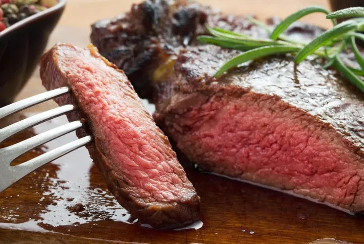 bifteck de faux-filet rôti moyen sur une assiette en bois avec du poivre et du sel