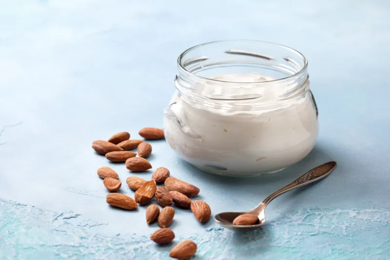almond yogurt in a glass jar on a blue concrete background