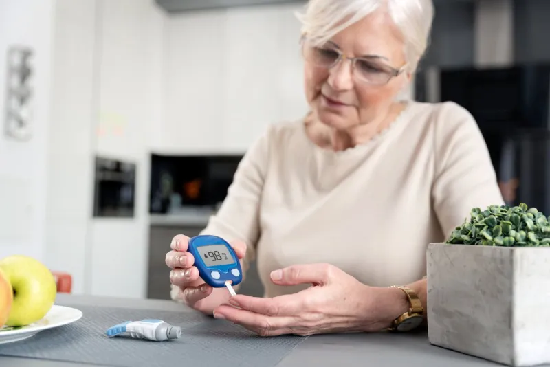 senior woman with glucometer checking blood sugar level at home diabetes, health care concept