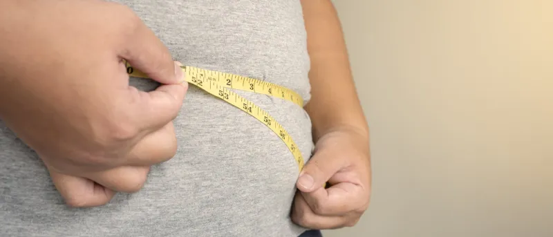 an obesity using measuring tape to show the real size chubby fat man using measure tape at his belly