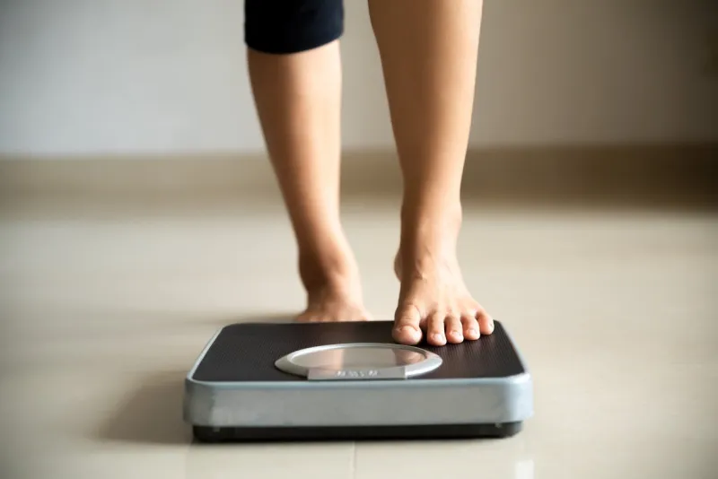 female leg stepping on weigh scales healthy lifestyle, food and sport concept