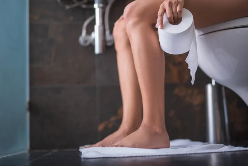 close up girl smooth legs locating in lavatory on cozy carpet she keeping bog roll in arm