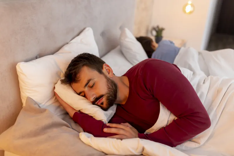 beautiful young couple in love wearing pajamas lying in bed, sleeping back to back