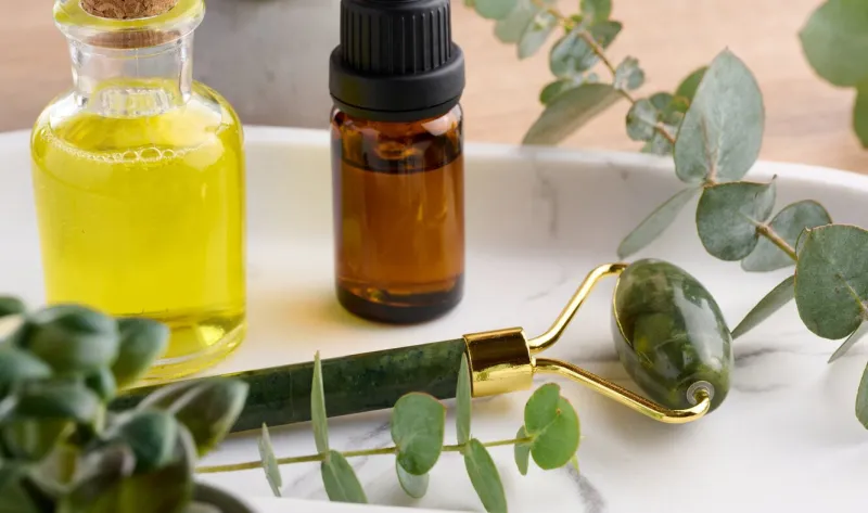 brown glass bottle with pipette and green stone roller massager on a brown wooden background, top view