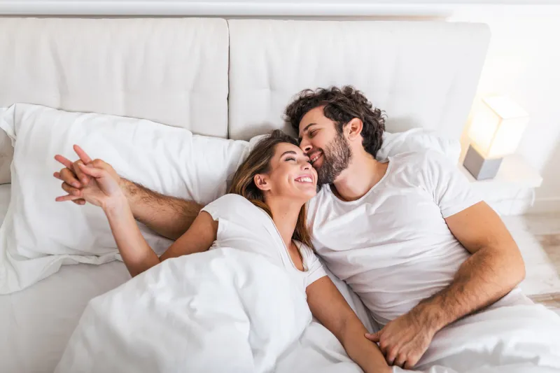 happy couple is lying in bed together enjoying the company of each otherhappy young couple hugging and smiling while lying on the bed in a bedroom at home