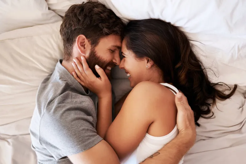 smile, bed and happy couple hug, relax and spending lazy morning together, bonding and intimacy on spain vacation happiness, marriage and top view of romantic man, woman or people embrace in bedroom