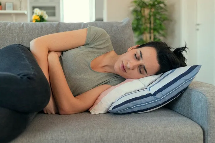 woman with abdomen problems in bed, she use hands to massage painful place people with diarrhea problem concept woman with menstrual pain