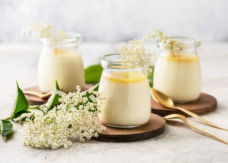 homemade creamy elder flowers panna cotta with lemon sauce in vintage glass jars on a light concrete background desserts without baking