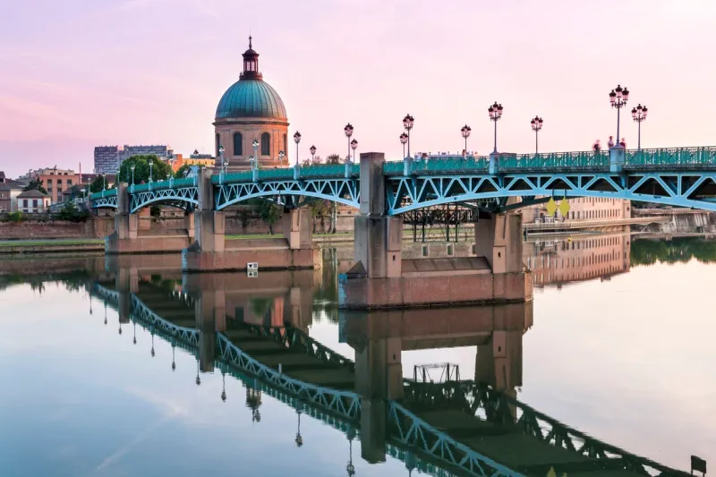 saint-pierre bridge reflecting in garonne river and dome de la grave at sunset in toulouse, france