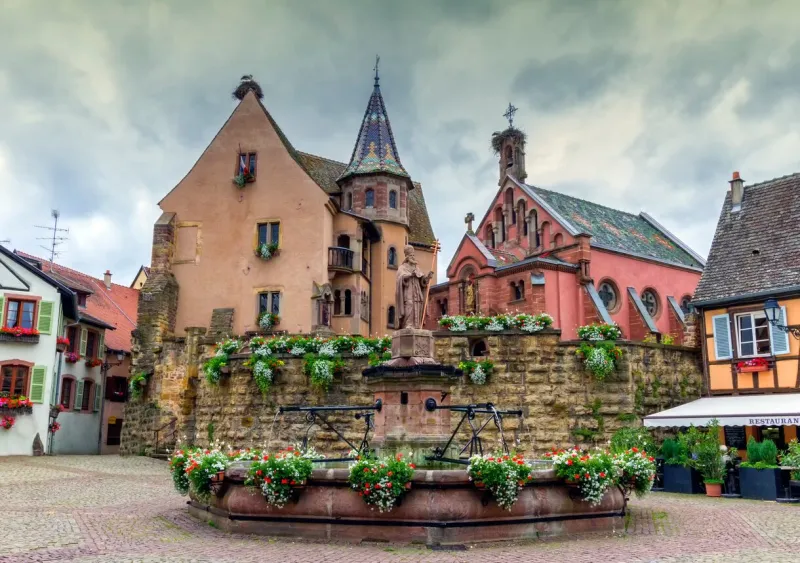 saint-leon fountain and traditional timbered houses in eguisheim, alsace, france