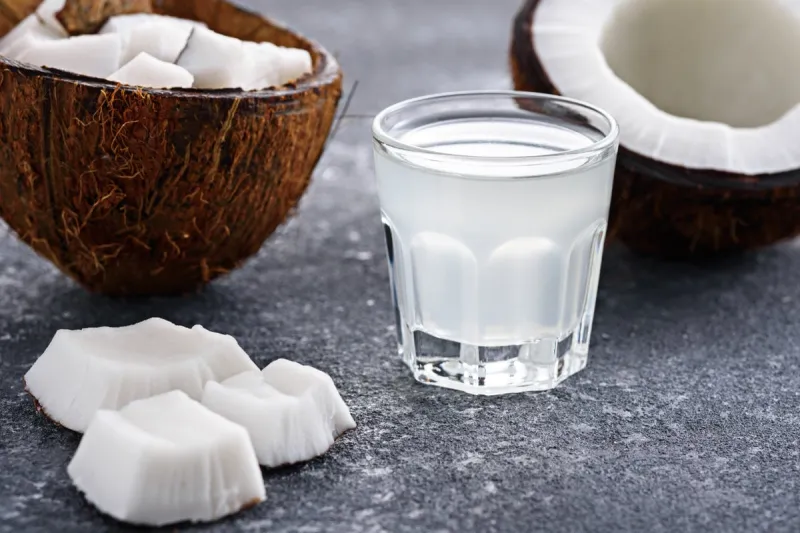 closeup coconut halves and coconut water in glass shot ongray background
