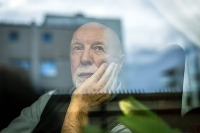 portrait of thoughtful senior man looking through window