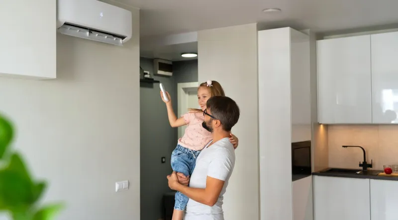 father kept to hand little daughter and turn on air conditioner using remote control happy family adjust comfortable temperature of cooler system