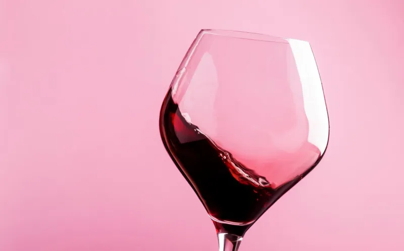 dry red wine, splash in glass, pink background, defocused in motion image, shallow depth of field