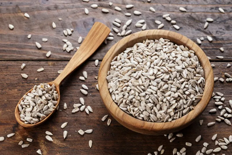 peeled sunflower seeds on a wooden background in a plate place for text