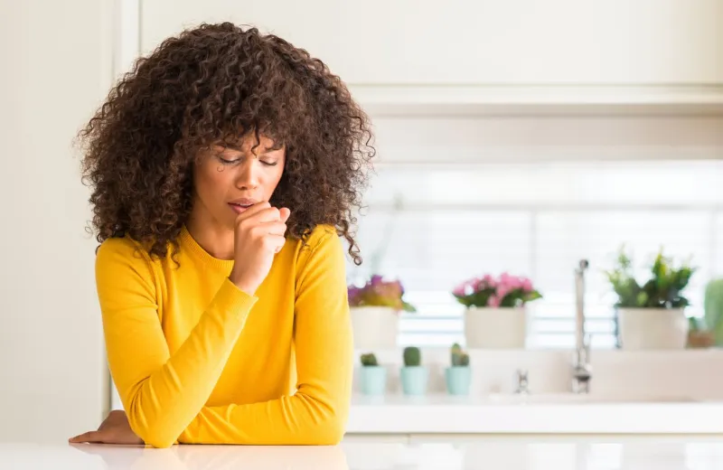 african american woman wearing yellow sweater at kitchen feeling unwell and coughing as symptom for cold or bronchitis healthcare concept