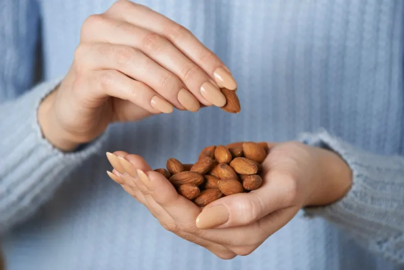 close up of woman holding handful of almonds