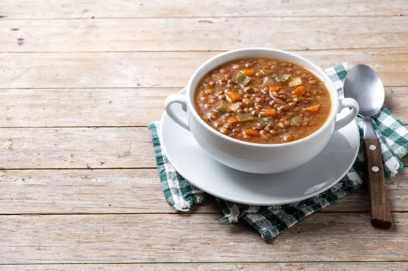 lentil soup with vegetables in bowl on wooden table